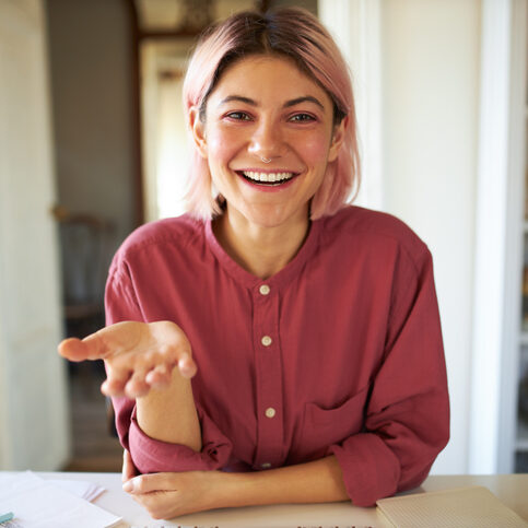 Woman smiling with pinkish hair smiling broadly while creating video marketing content with Beings. Woman smiling with pinkish hair smiling broadly while creating video marketing content with Beings.